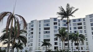 Een modern hotel met meerdere verdiepingen, een zwembad en palmbomen.