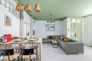 A dining area with a table set for four, a sofa, and a painting on the wall.