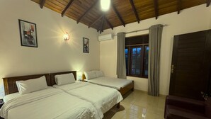 Una habitació d'hotel amb dos llits, un sostre de fusta, una finestra amb cortines i una porta.