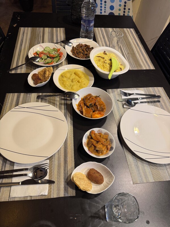 A dining table with various dishes, utensils, and a water bottle.