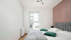 Ein Schlafzimmer mit einem Bett, einem Fenster, einer Heizung und einer Deckenleuchte.