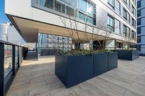 Un edificio moderno con amplios ventanales y un área exterior cubierta con macetas.
