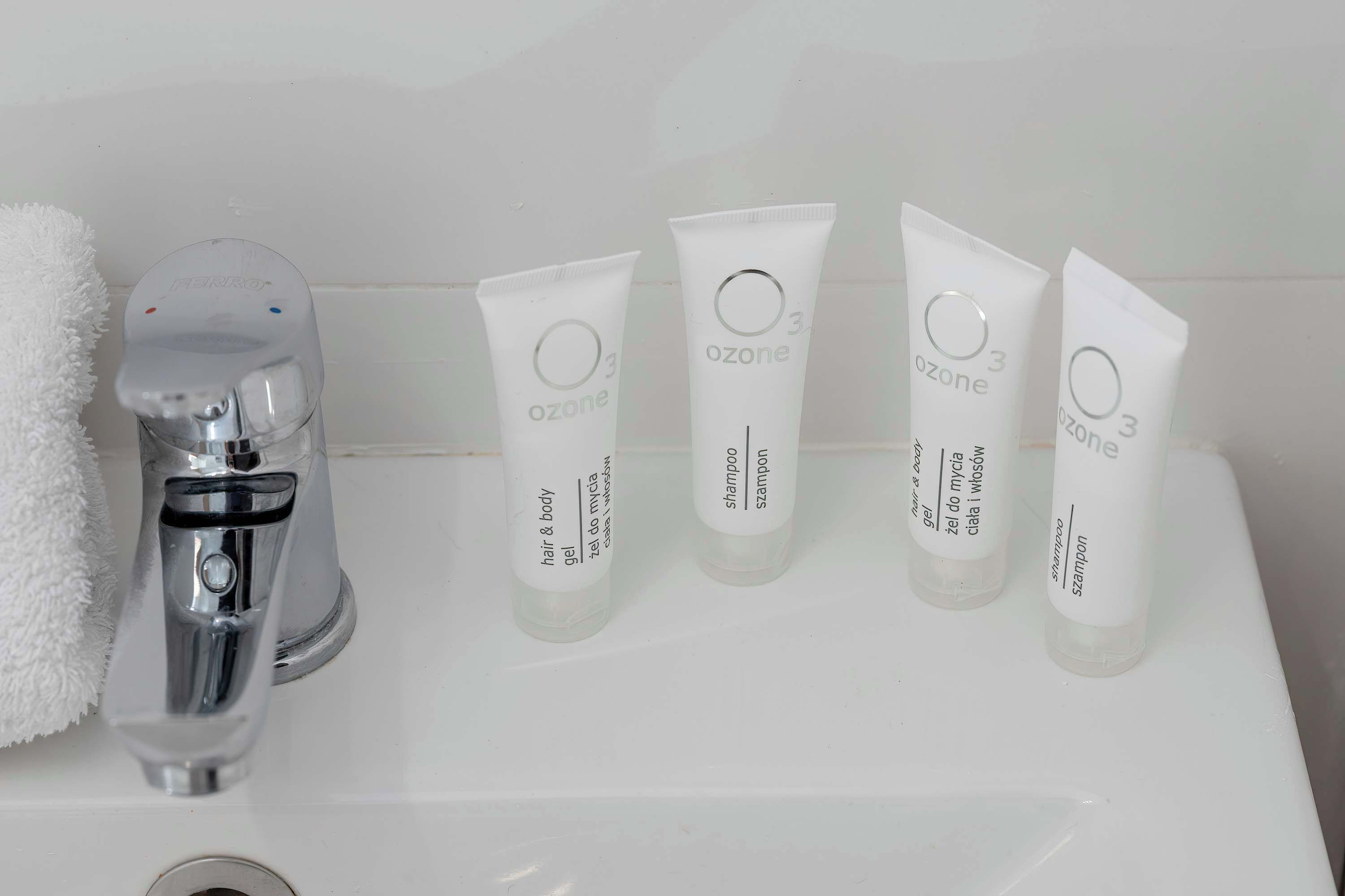 A bathroom sink with five tubes of Ozone hair and body gel, two tubes of Ozone shampoo, and one tube of Ozone body wash.