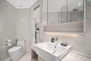 Ein modernes Badezimmer mit Toilette, Waschbecken und Dusche.