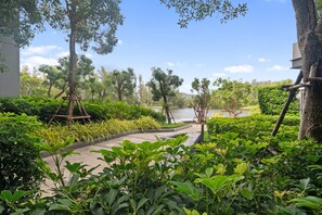 A pathway leading to a body of water, surrounded by lush greenery and trees.
