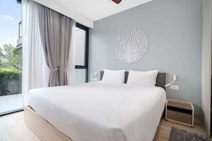 Ein modernes Schlafzimmer mit einem großen Bett, einem Wandkunstwerk und Blick auf Grünflächen.