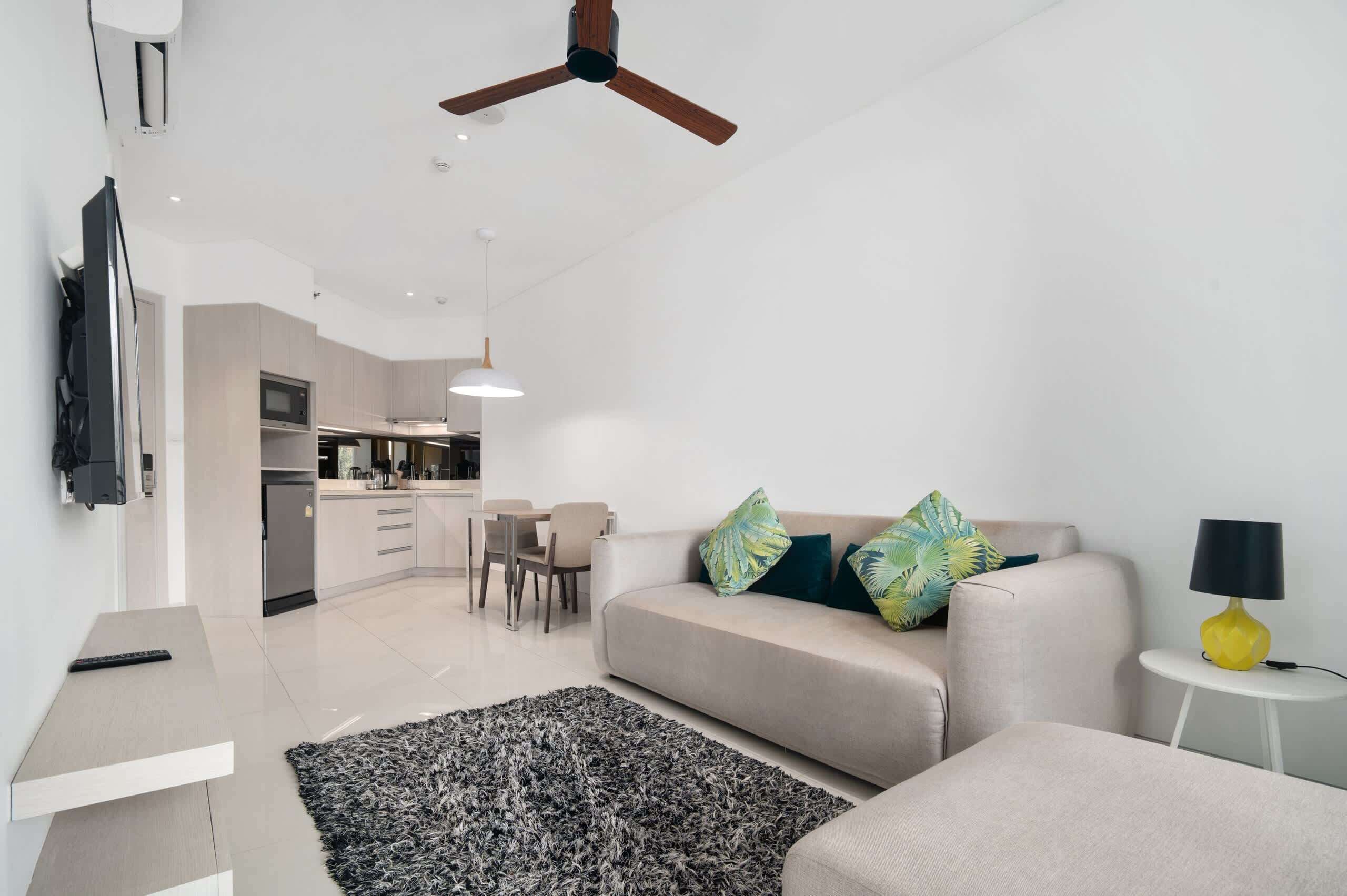 Un salon moderne comprenant un canapé, une table basse, un téléviseur et un coin repas avec des chaises et une table.