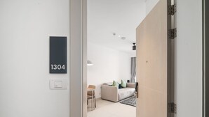Habitació d'hotel moderna amb un disseny minimalista, que inclou un sofà, una taula de dinar i una finestra gran.