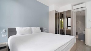 Habitació d'hotel moderna amb un llit gran, un armari encastat i un bany amb dutxa i vàter.
