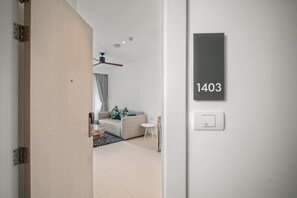 A modern interior with a sofa, a small table, and a ceiling fan. A door with a number plate '1403' is visible.