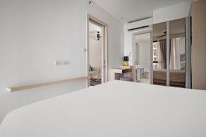 A hotel room with a large bed, a desk, a chair, and a wardrobe.