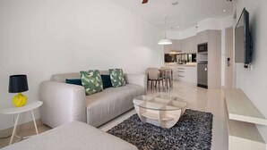 Een moderne woonkamer met een bank, salontafel en een plafondventilator.