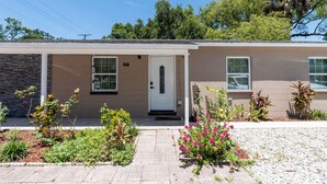 A single-story building with a beige exterior, a white door, and a small porch area. - Spacious Home in CentralTampa near all attractions (Tampa)