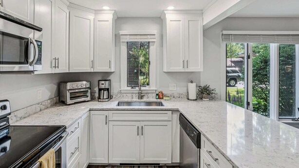 A modern kitchen with white cabinets, a built-in oven, a microwave, and a dishwasher. - Condo Steps from Lake Pinneo, Fairway Village (Hartford)
