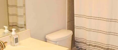 Un baño con un lavabo blanco, un inodoro y una cortina de ducha a rayas.