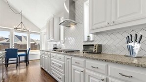 Una cocina con gabinetes blancos, encimera de granito y horno empotrado.