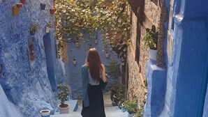A narrow stone pathway leading to a building with a blue facade and potted plants. - Your Second Home Awaits – Cozy Stay with Outstanding Service (Agadir)