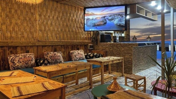 A cozy room with wooden furniture, a television, and a view of the sea. - Your Second Home Awaits – Cozy Stay with Outstanding Service (Agadir)