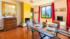 Un comedor con una mesa preparada para dos personas, un televisor y vistas de montañas a través de una ventana.