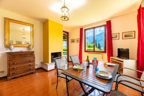 Un coin repas avec une table en bois, des chaises, un téléviseur et une cheminée.