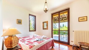 Un dormitorio con cama, una mesa, una silla, una lámpara y vistas al exterior.