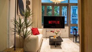 A modern living room with a sofa, a coffee table, and a TV displaying 'NETFLIX'. - The Train Street Residence Ly Nam De (Hanoi)