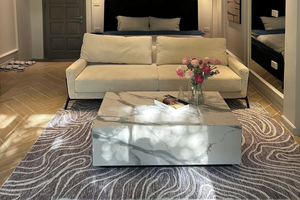 Un salon moderne avec un canapé, une table basse et un lit en arrière-plan.