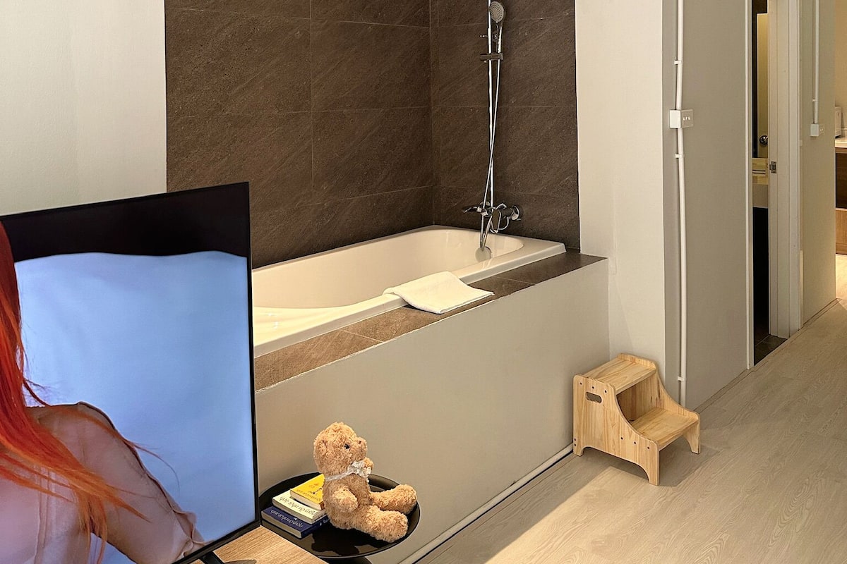 Une salle de bain moderne équipée d’une douche, d’une baignoire et d’un petit tabouret en bois.