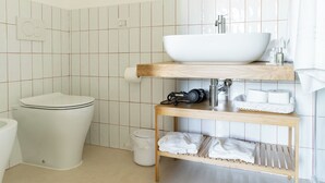 Ett modernt badrum med ett vitt handfat, en toalett och en dusch.