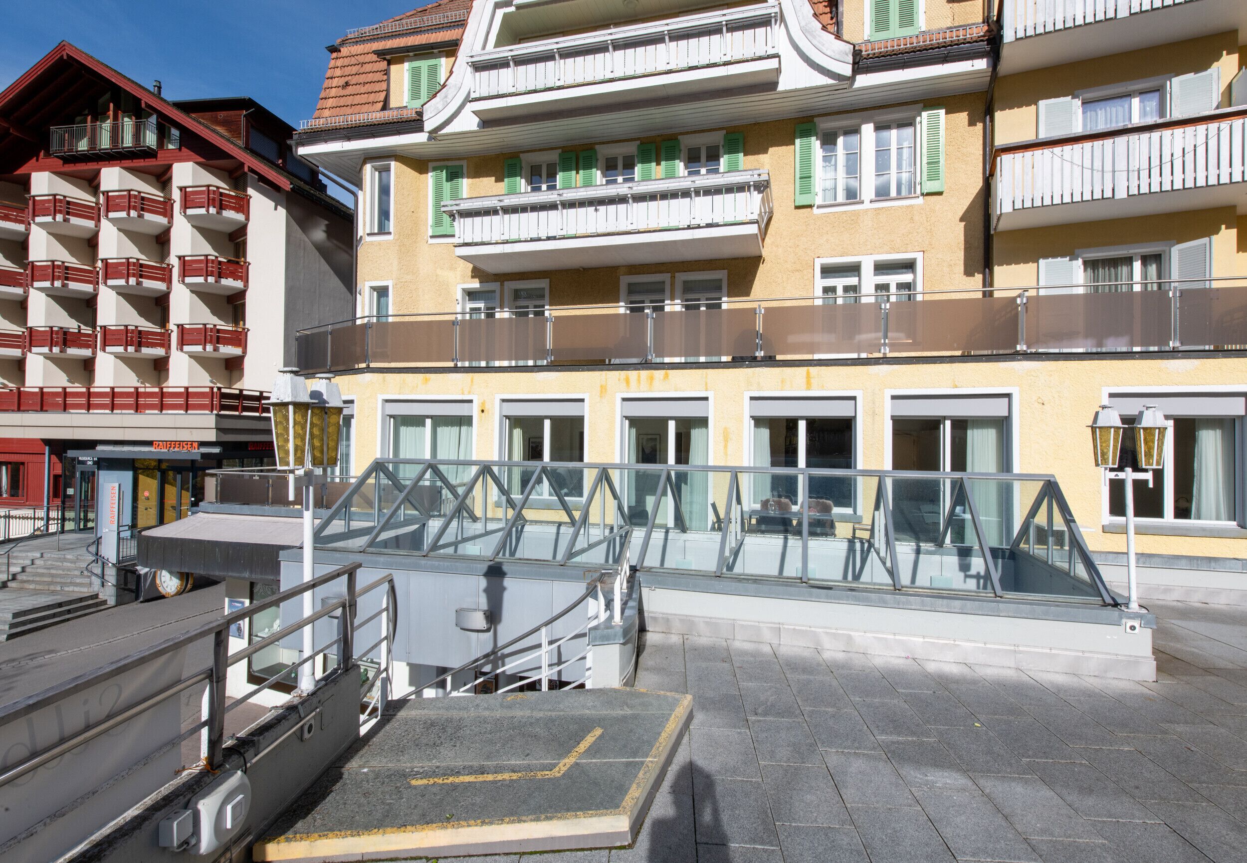 Un hotel a più piani con balconi, un ingresso in vetro e una rampa di accesso.