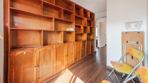 Ein geräumiges Zimmer mit einem großen Bücherregal aus Holz, einem Klappsessel und einer Tür zu einem weiteren Raum.