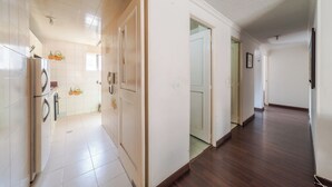 Ein Flur mit einer Küchenzeile links, inklusive Kühlschrank und Fliesenboden.