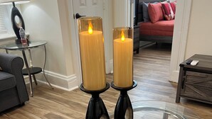 A modern living room with a glass coffee table, two candles on black stands, a grey sofa, a small side table with a lamp, and a red sofa in the background. - Outstanding spacious 2-bedroom Apt in downtown Cincinnati with many amenities (Cincinnati)