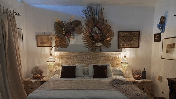 A bedroom with a large bed, decorative wall art, and a nightstand with a lamp. - Belle propriété de style Caraïbes, confortable chambre d'hôtes, piscine privée (Las Terrenas)