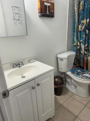 Une salle de bain avec un lavabo blanc, des toilettes et un rideau de douche.