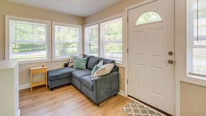A room with a gray sectional sofa, a small wooden side table, and a white door with a glass window. - Lakeview Lodge - Stay for 6 (Lake Geneva)