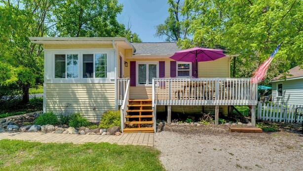 A small, single-story house with a front deck and a covered patio area. - Lakeview Lodge - Stay for 6 (Lake Geneva)