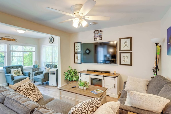 A living room with a ceiling fan, a fireplace, and a television mounted on the wall. - Lakeview Lodge - Stay for 6 (Lake Geneva)