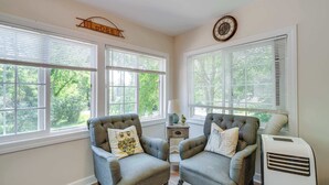 A room with two grey armchairs, a small table with a lamp, and a white air conditioner. - Lakeview Lodge - Stay for 6 (Lake Geneva)