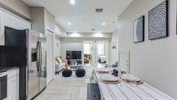 A modern kitchen with a built-in refrigerator, a dining area with a table set for four, and a living room with a sofa and TV. - Modern large 2-bedroom near Philadelphia Convention Center!!! (Philadelphia)
