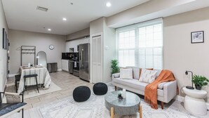 A modern living room with a sofa, coffee table, and dining area. - Modern large 2-bedroom near Philadelphia Convention Center!!! (Philadelphia)