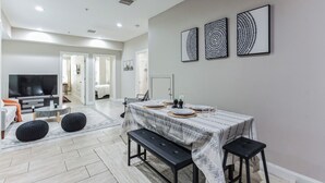 A modern living room with a large TV, a dining area with a table set for four, and a hallway leading to other rooms. - Modern large 2-bedroom near Philadelphia Convention Center!!! (Philadelphia)