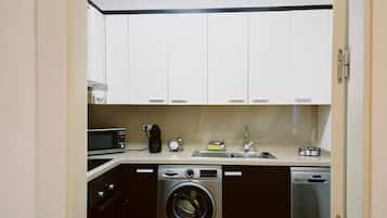 A compact kitchen with a washing machine, dishwasher, microwave, and a coffee maker.