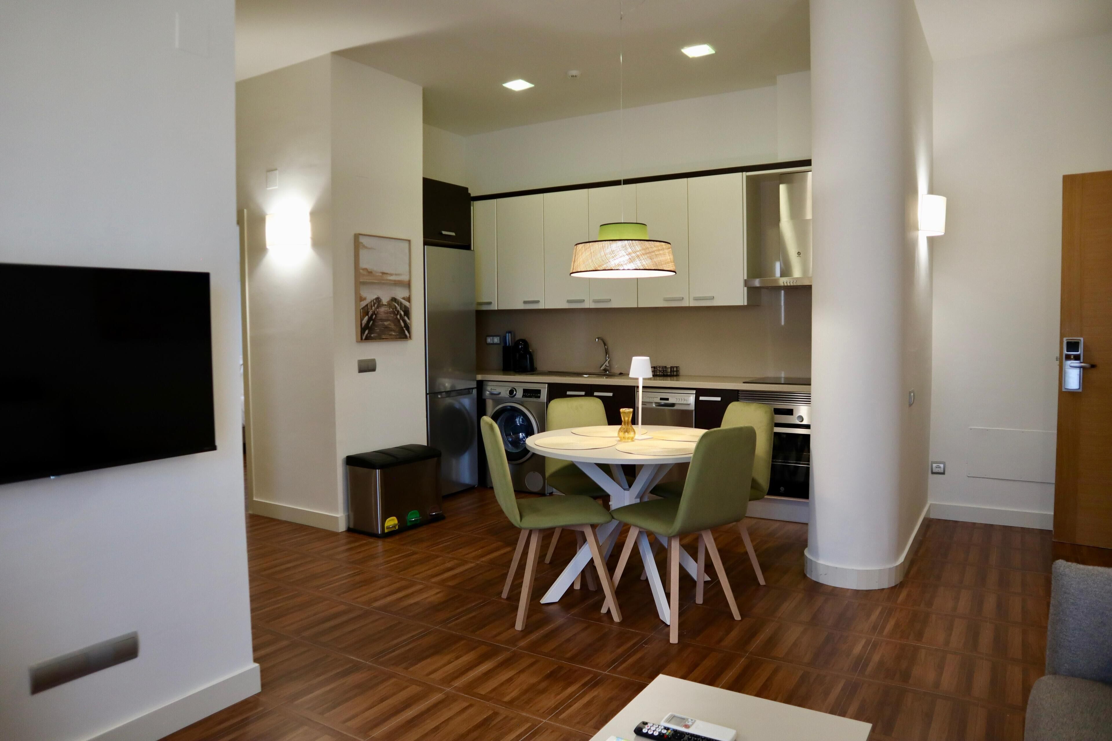 Una cocina moderna con comedor, electrodomésticos integrados y un televisor de pantalla plana.