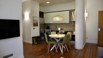 Una cocina moderna con comedor, electrodomésticos integrados y un televisor de pantalla plana.