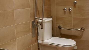 Un baño con inodoro, barras de apoyo y zona de ducha.