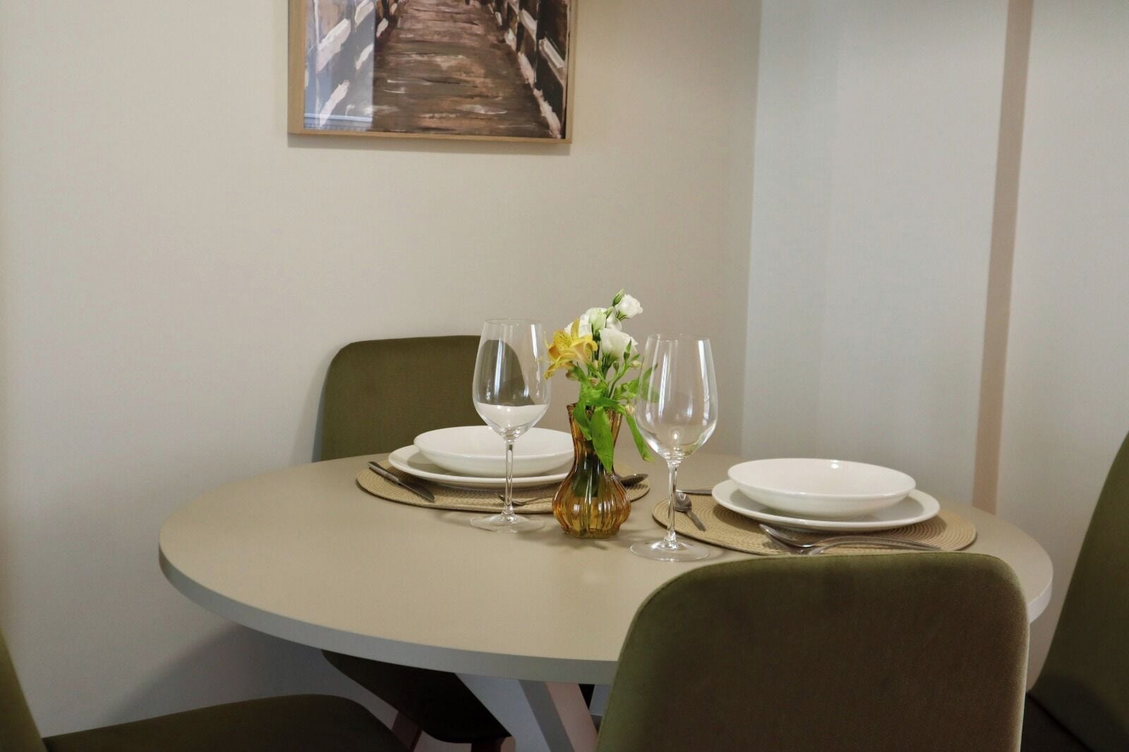 Une table à manger dressée avec des assiettes, des verres à vin et un vase rempli de fleurs.