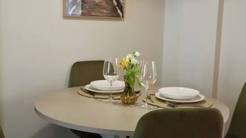Une table à manger dressée avec des assiettes, des verres à vin et un vase rempli de fleurs.