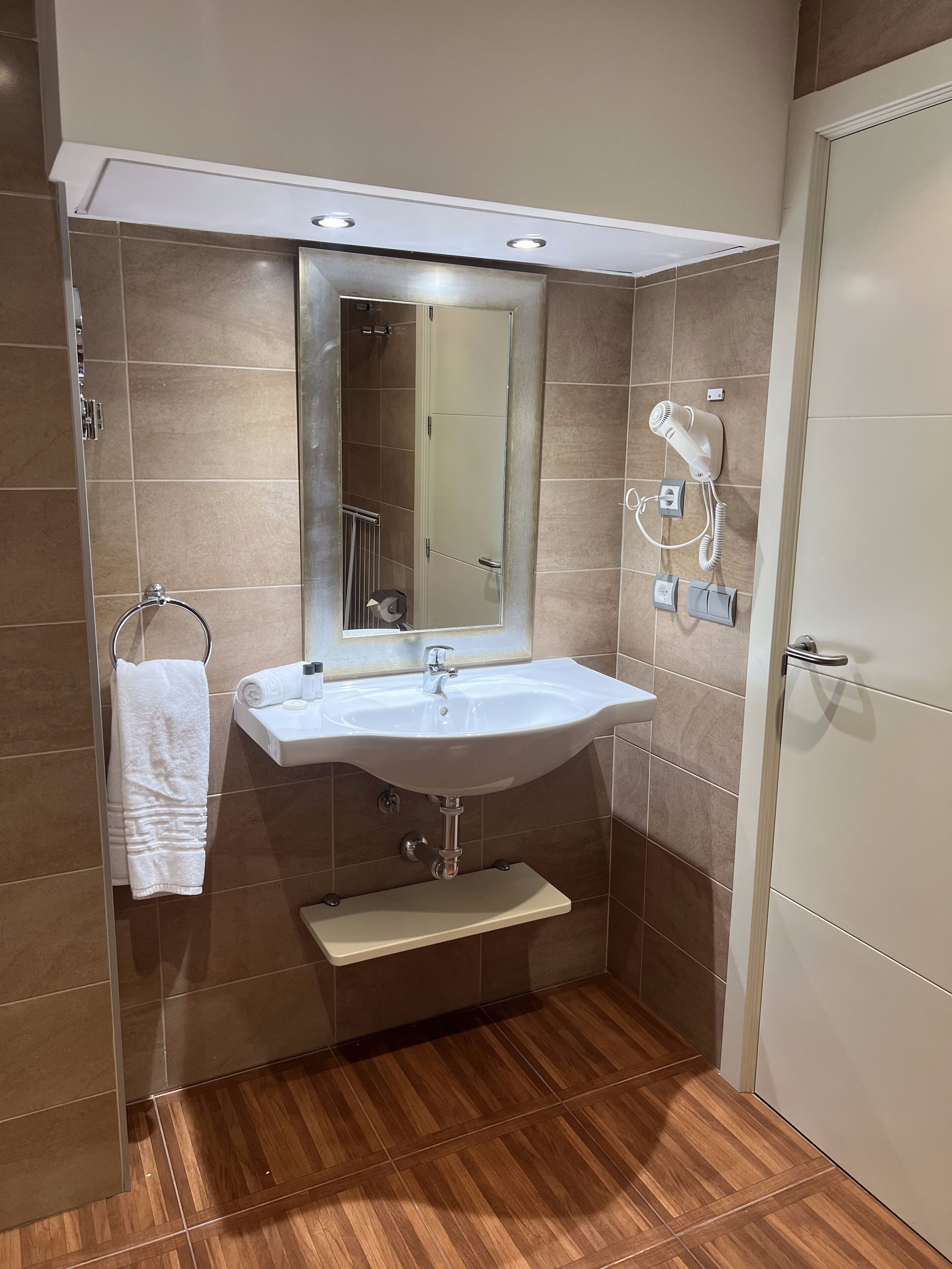 A modern bathroom with a white sink, mirror, and towel rack.