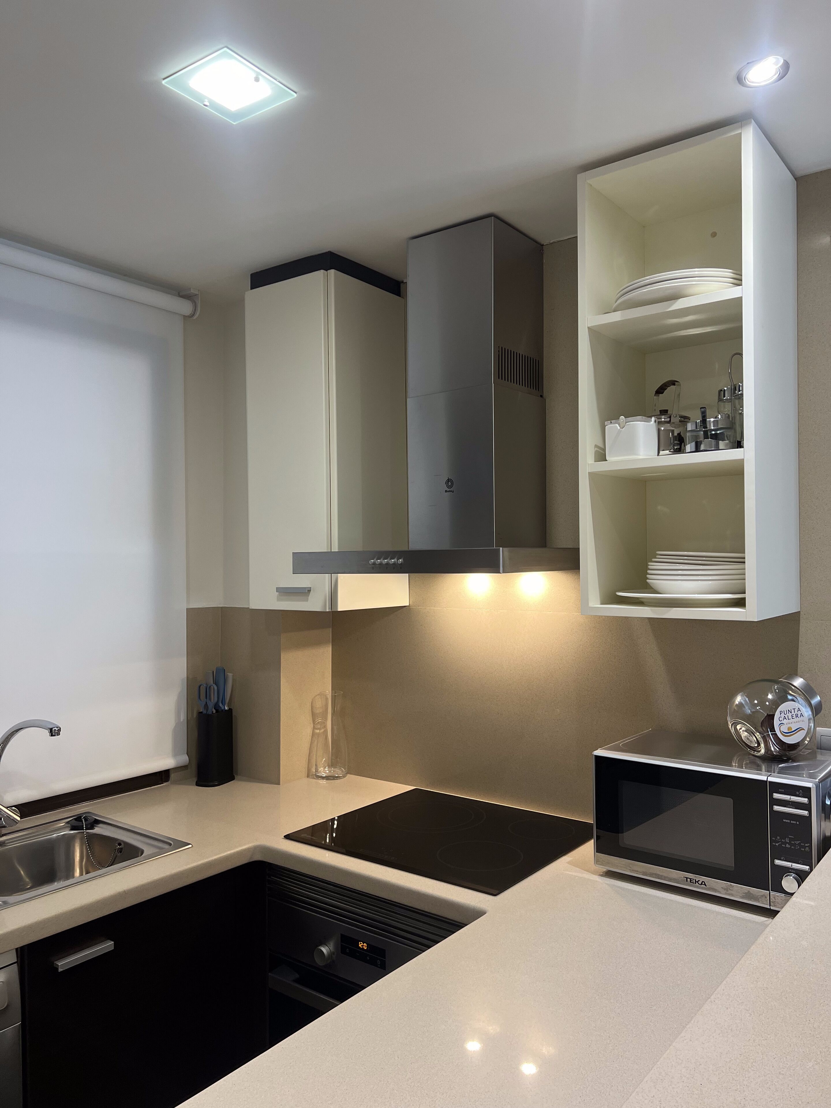 A modern kitchen with a built-in microwave, a sink, and a stainless steel range hood.